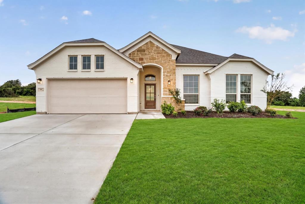 321 Skeen Peak Springtown, TX 76082 - Photo 2 of 37 White brick facade with stone accents and dark shingle roofing