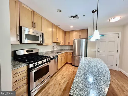 a kitchen with stainless steel appliances granite countertop a stove refrigerator and microwave