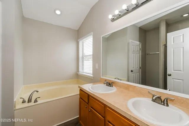 a bathroom with a tub a sink and mirror