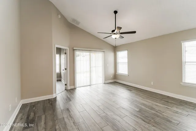 a view of an empty room with window and wooden floor