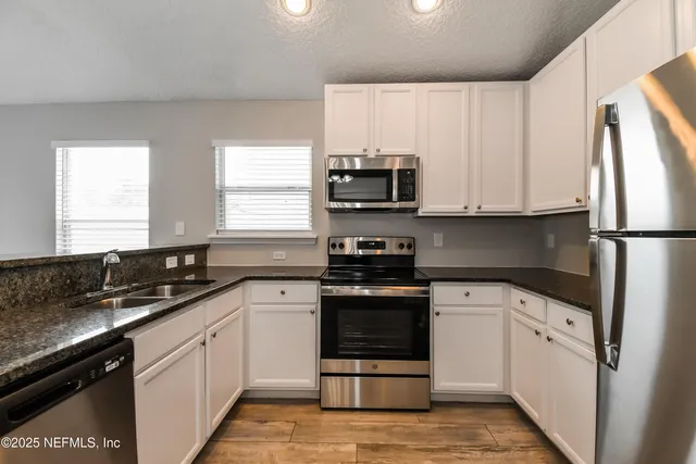 a kitchen with granite countertop a sink stove and refrigerator