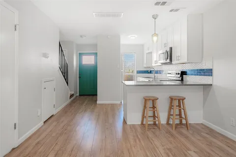 a kitchen with stainless steel appliances granite countertop a table chairs stove and cabinets