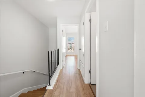 a view of a hallway with wooden floor and a bathroom