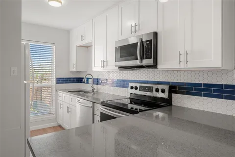 a kitchen with stainless steel appliances granite countertop a stove a sink and a microwave