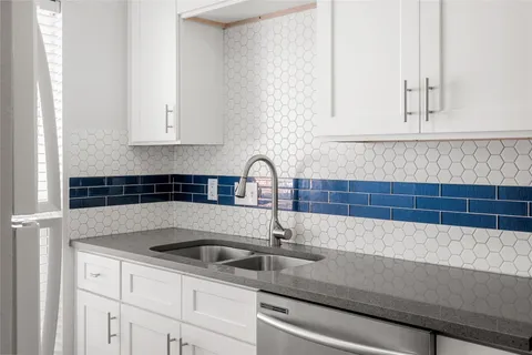 a kitchen with granite countertop white cabinets and a sink