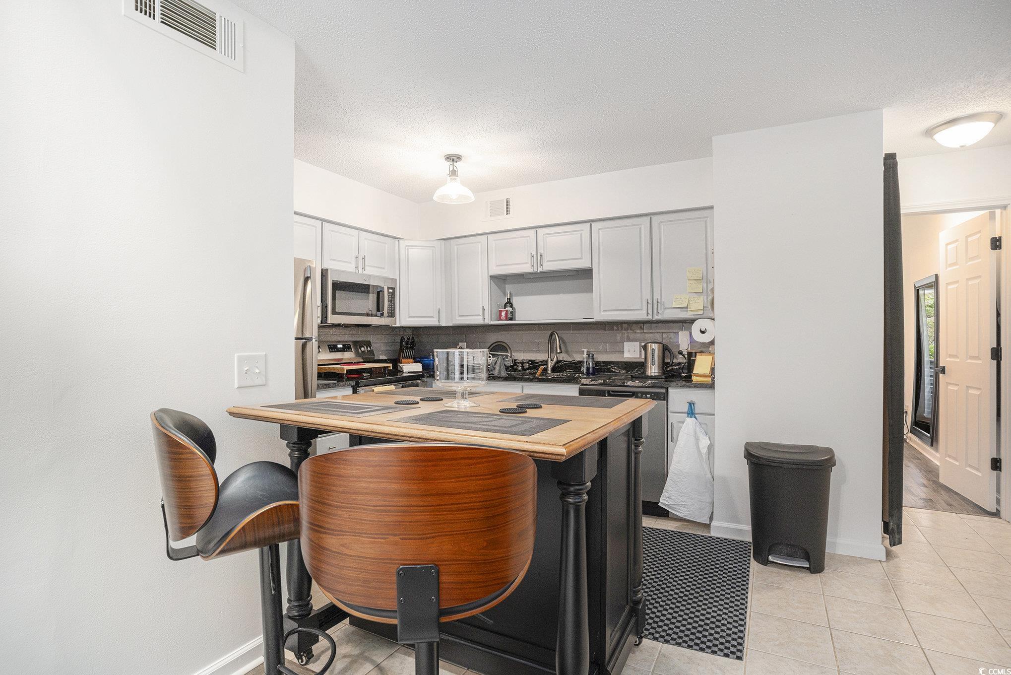 400 Cambridge Circle, Unit L8 Murrells Inlet, SC 29576 - Photo 3 of 22 Kitchen featuring tasteful backsplash, light tile patterned floors, appliances with stainless steel finishes, a textured ceiling, and dark countertops