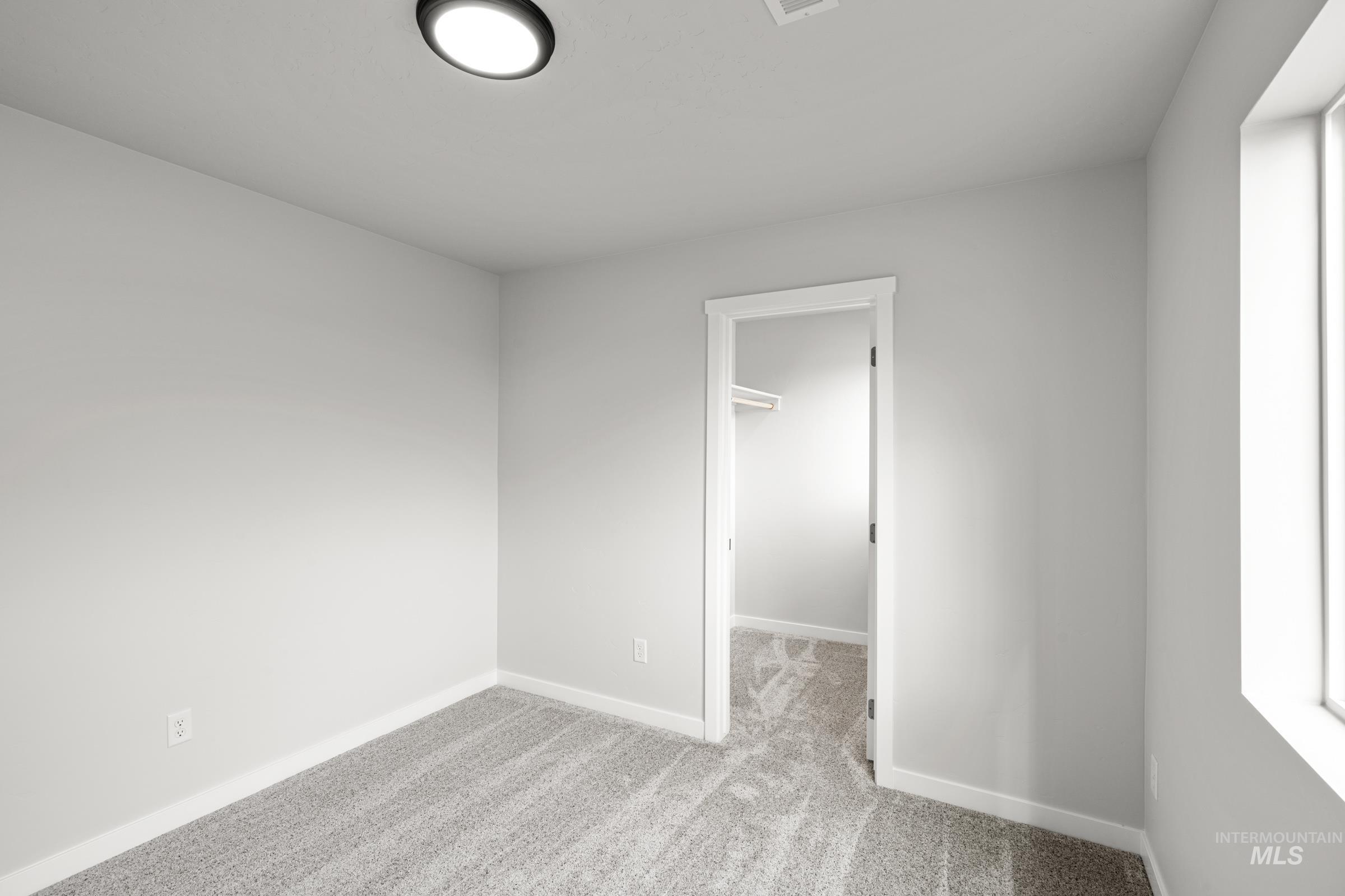 14056 Shiny Spruce Street Caldwell, ID 83607 - Photo 17 of 25 Light gray carpet and walls create a neutral palette in this room, featuring a window for natural light and a recessed ceiling light fixture