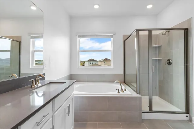 a bathroom with a granite countertop tub sink double vanity and window