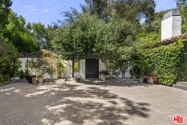 a view of a house with a tree and sitting area