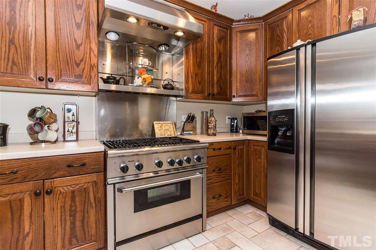 6521 Arbor Grande Way Raleigh, NC 27615 - Photo 3 of 12 a kitchen with stainless steel appliances granite countertop a refrigerator a stove and a sink with wooden cabinets