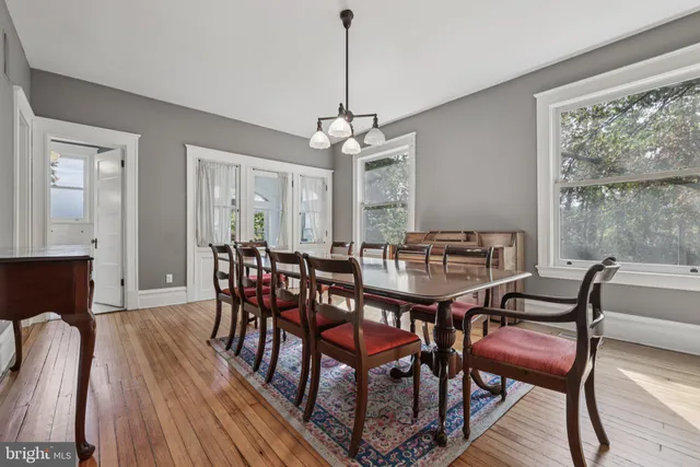 a open kitchen with stainless steel appliances granite countertop a refrigerator a oven a dining table and chairs with wooden floor