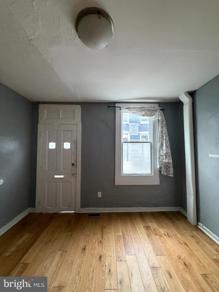 1607 Lemmon Street Baltimore, MD 21223 - Photo 4 of 30 an empty room with wooden floor and windows