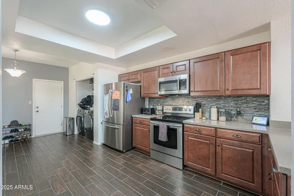 a kitchen with stainless steel appliances granite countertop a stove top oven a sink dishwasher a refrigerator and cabinets with wooden floor