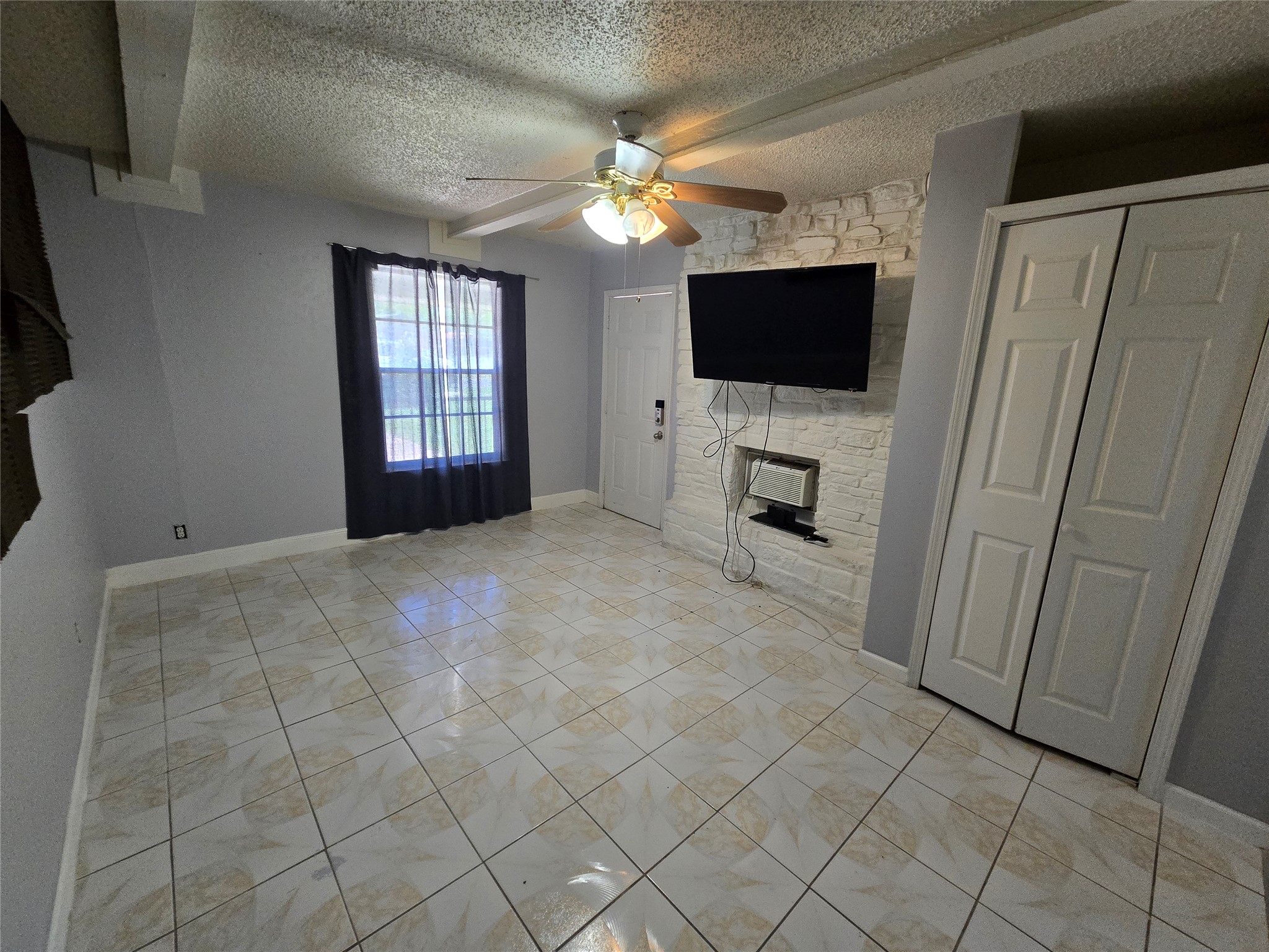 10605 Newmont Road, Unit B Austin, TX 78758 - Photo 3 of 10 Unfurnished efficiency with a textured ceiling, a fireplace, a ceiling fan, and baseboards