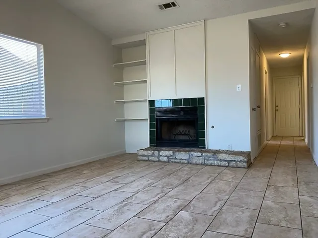 a view of an empty room with a fireplace and a window