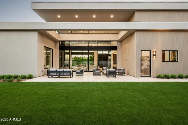 a view of a patio with couches table and chairs with potted plants and big yard