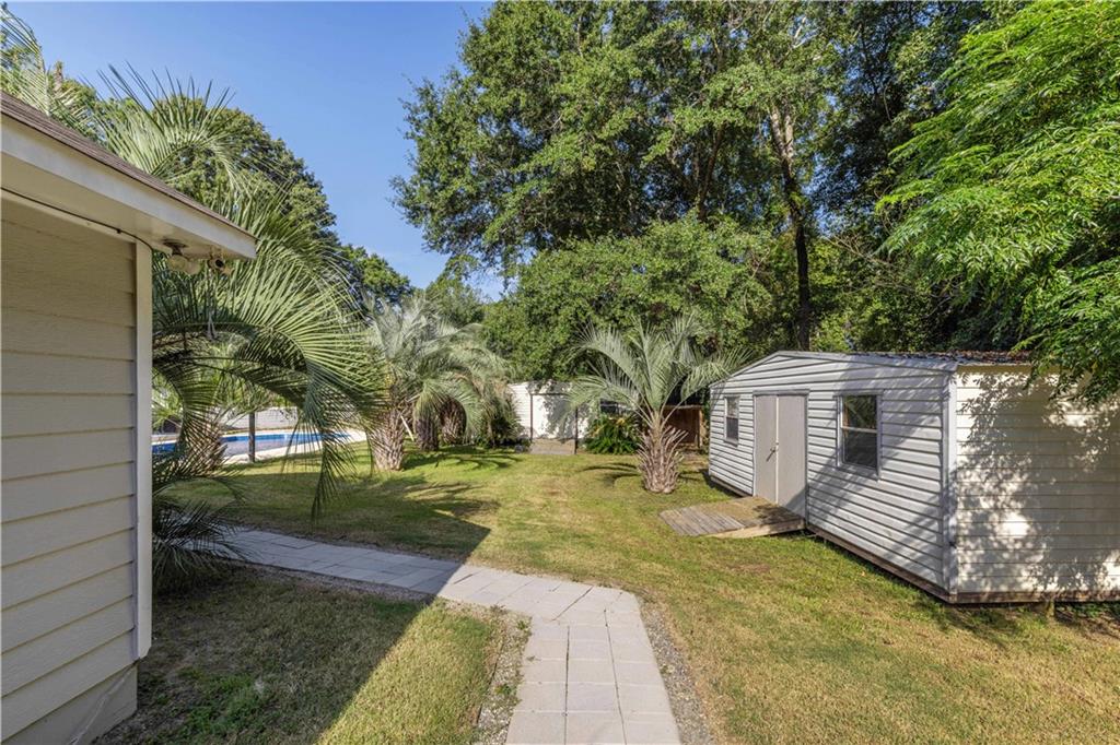 4 Ford Road Phenix City, AL 36869 - Photo 26 of 52 Expansive backyard featuring a paver pathway, mature palm trees, a storage shed, and a visible swimming pool