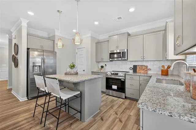 a kitchen with stainless steel appliances granite countertop a refrigerator a sink dishwasher a stove and white countertops with wooden floor