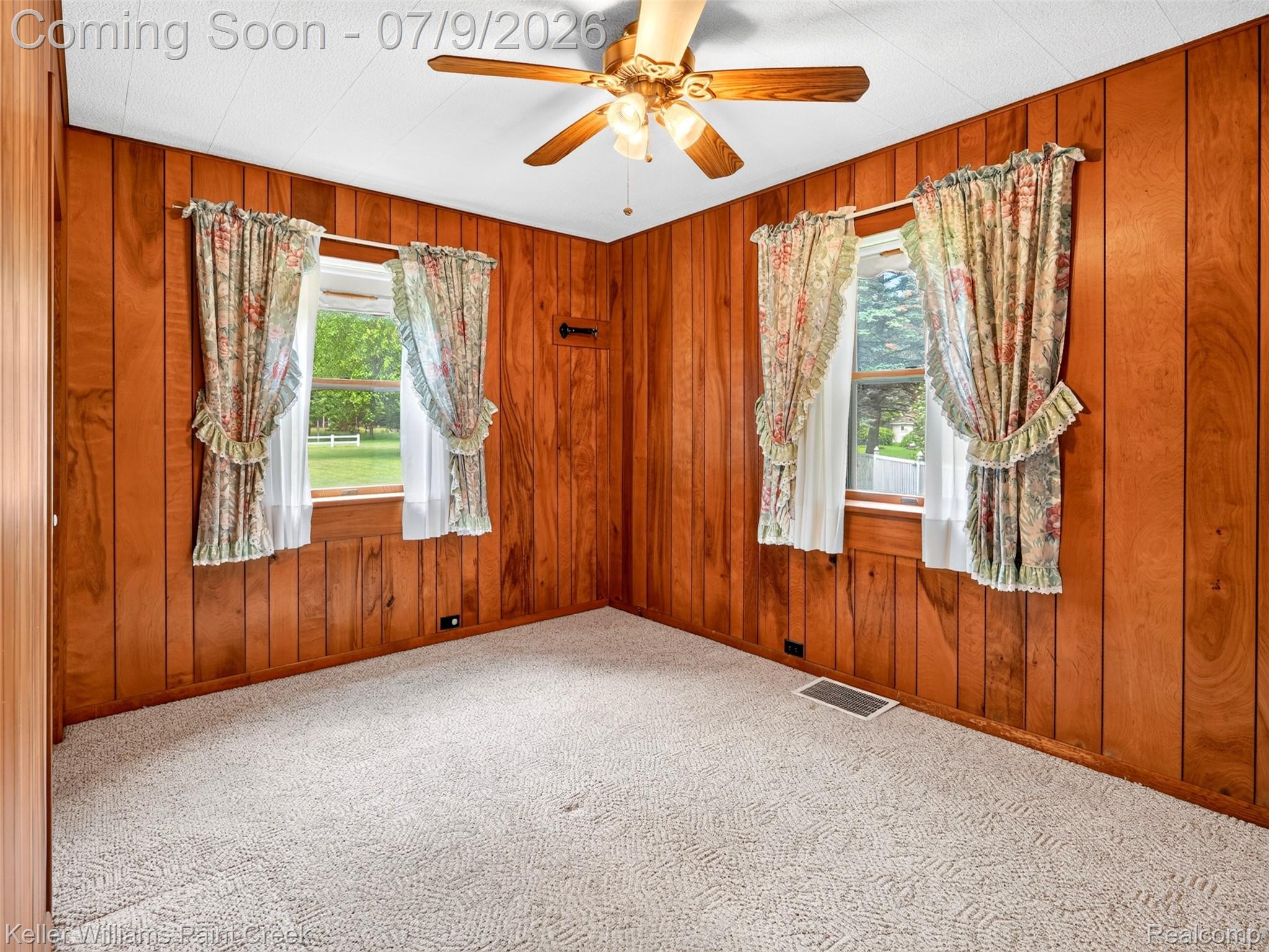 204 Russell Road Kawkawlin, MI 48631 - Photo 33 of 82 Room featuring wood paneling on walls, two windows, and a ceiling fan with light fixture