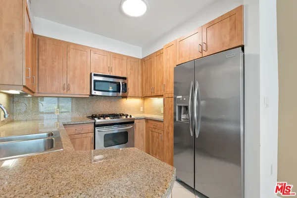 a kitchen with stainless steel appliances granite countertop a refrigerator a stove a sink and a microwave