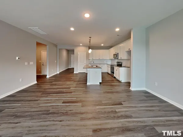 a view of kitchen with kitchen island a sink wooden floor and living room view