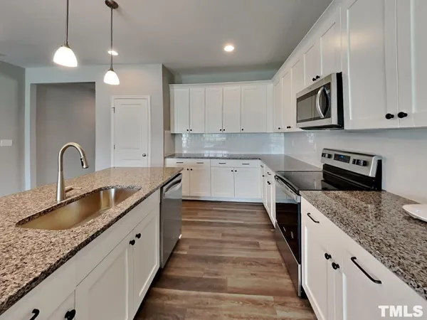 a large kitchen with granite countertop a sink and dishwasher a stove top oven with wooden floor