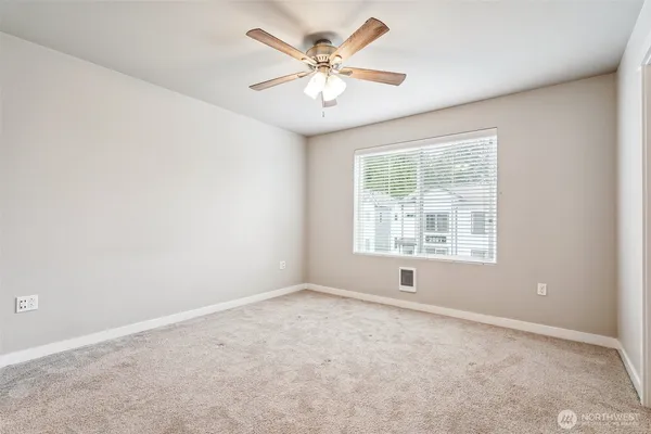 an empty room with windows and ceiling fan