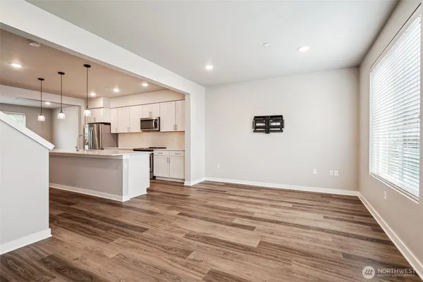 a view of kitchen with kitchen island wooden floors and stainless steel appliances