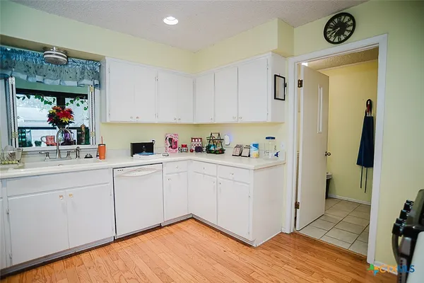 a kitchen with stainless steel appliances a stove a sink a refrigerator white cabinets and wooden floor