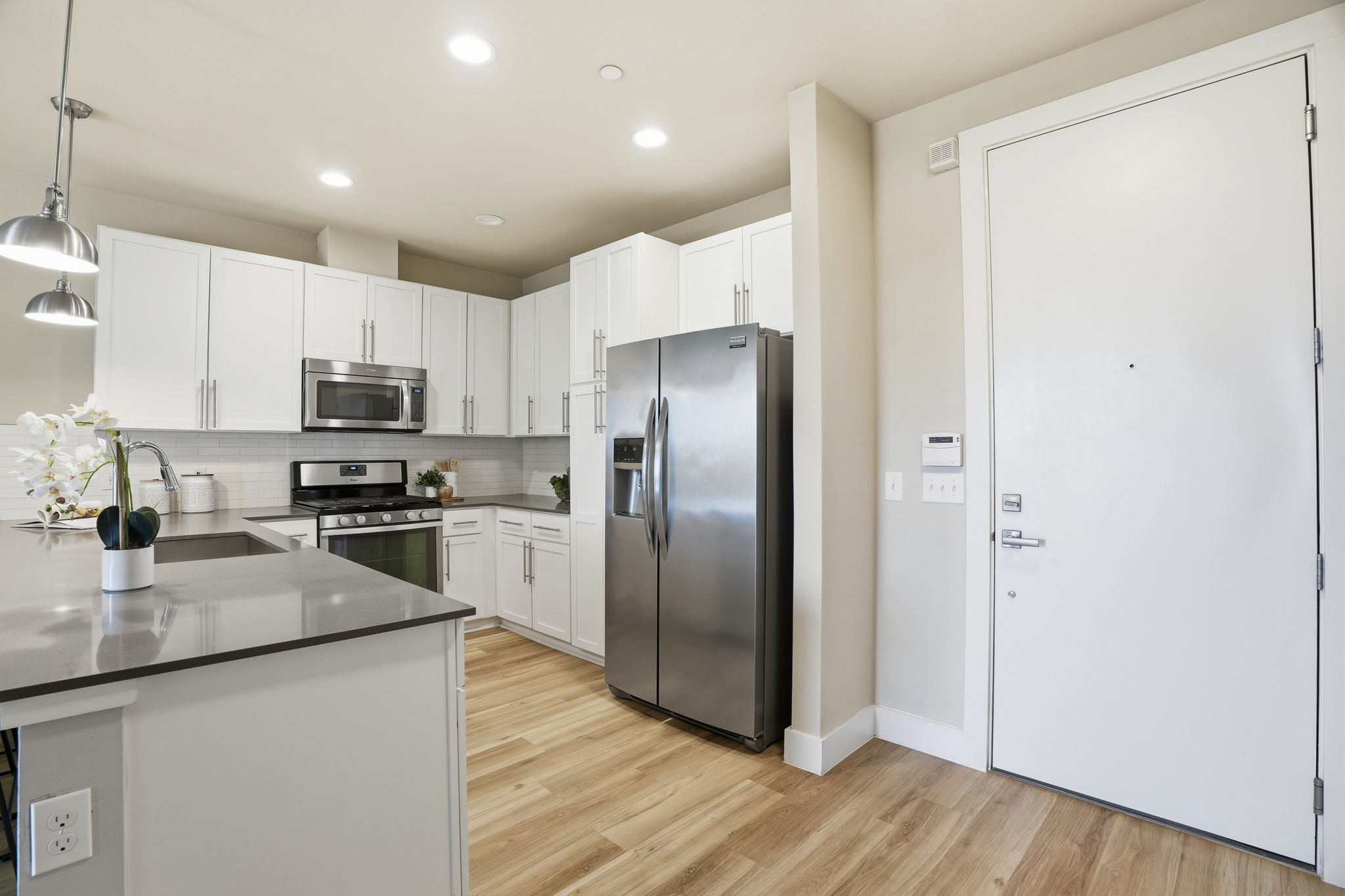 2805 Dulce Lane, Unit 1002 Austin, TX 78704 - Photo 9 of 23 Kitchen with pendant lighting, stainless steel appliances, white cabinets, light wood finished floors, and backsplash