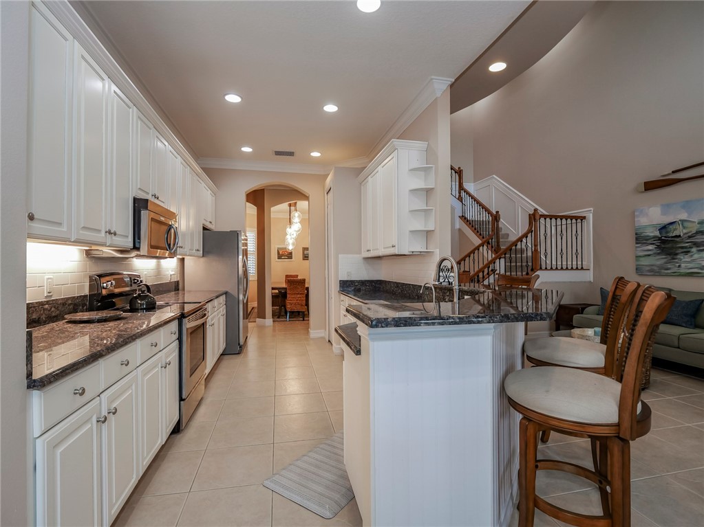 4570 Bridgepointe Way, Unit 148 Vero Beach, FL 32967 - Photo 9 of 32 a large kitchen with stainless steel appliances granite countertop a stove a sink dishwasher and a refrigerator with wooden floor