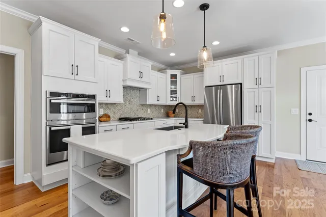 a kitchen with stainless steel appliances granite countertop a sink a stove a refrigerator and island with wooden floor