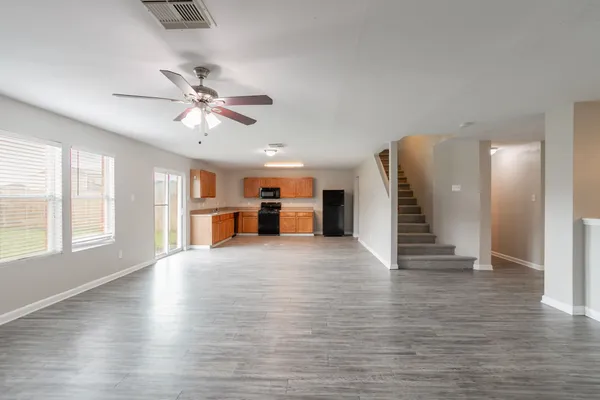 a view of an empty room with a window and wooden floor