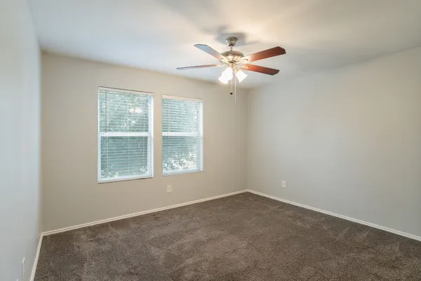 an empty room with windows and fan