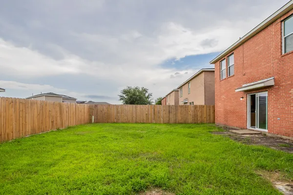 a view of a backyard with plants and brick wall