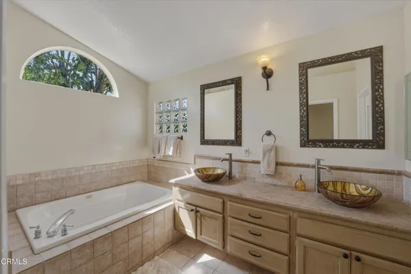 a bathroom with a granite countertop tub sink and mirror