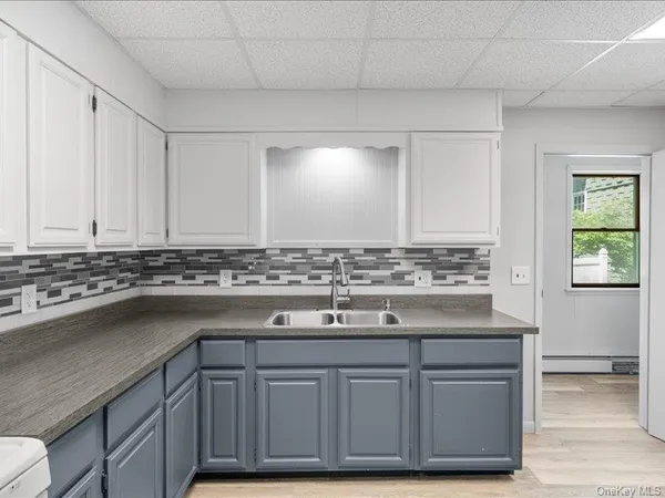 a view with granite countertop a sink and dishwasher a stove with wooden floor