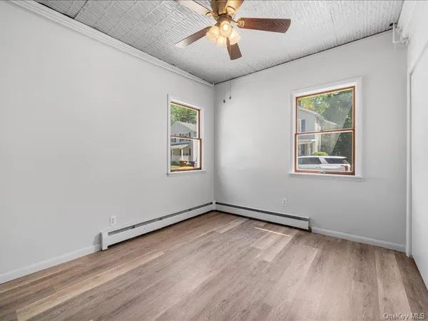an empty room with wooden floor chandelier and windows