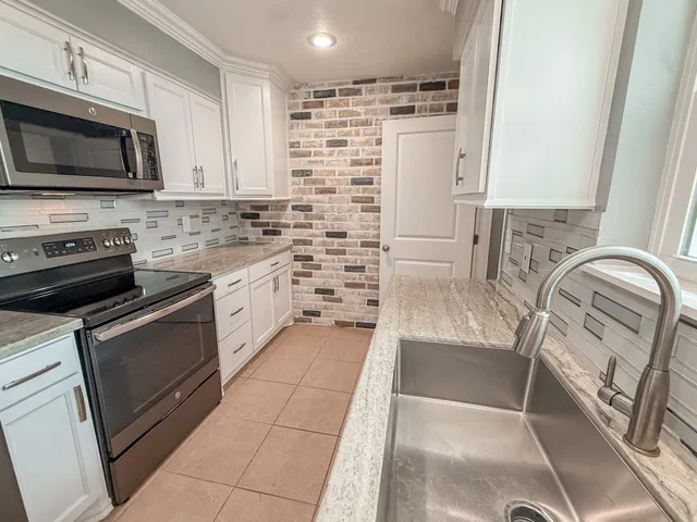 a kitchen with granite countertop a sink a stove a microwave and cabinets