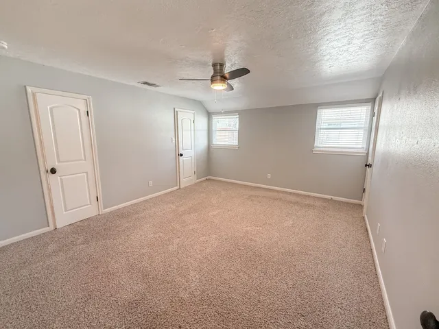 an empty room with windows and fan