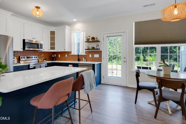 a dining room with wooden floor a chandelier a wooden table and chairs