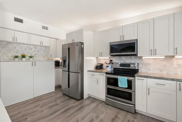 a kitchen with stainless steel appliances white cabinets a sink and a stove