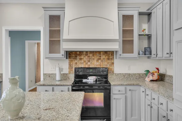 a kitchen with granite countertop a stove oven and white cabinets