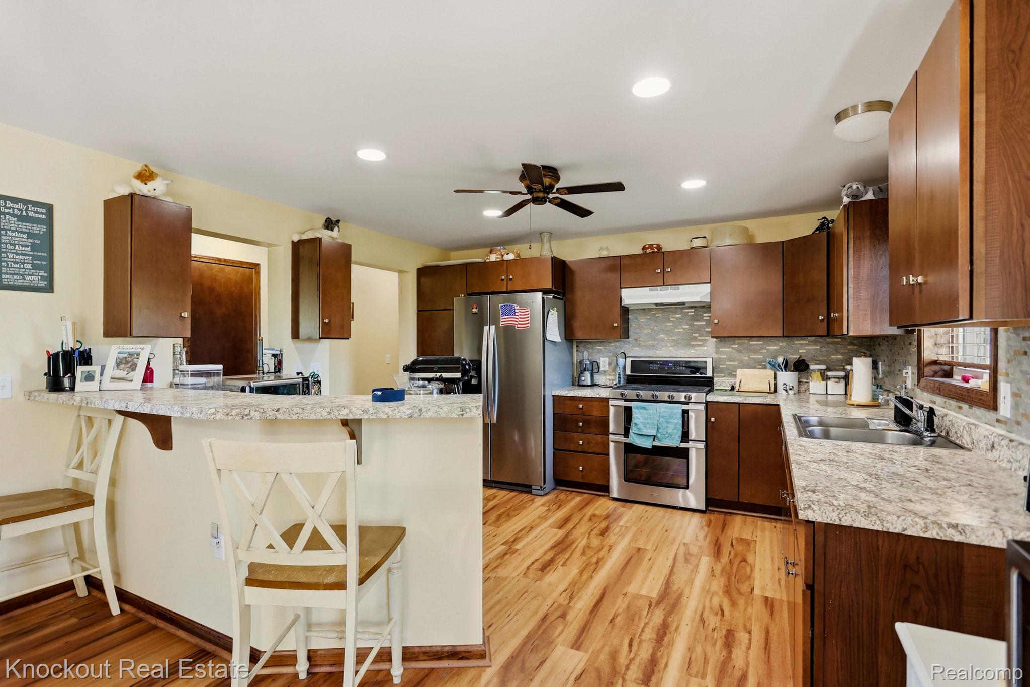 5727 Mackinaw Road Saginaw, MI 48604 - Photo 17 of 60 Kitchen featuring wood-finish flooring, recessed lighting, a ceiling fan, a breakfast bar, and stainless steel appliances