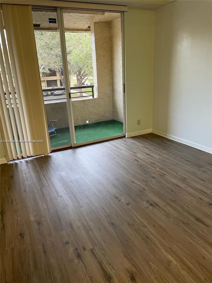 651 Lyons Road, Unit 10201 Coconut Creek, FL 33063 - Photo 13 of 16 an empty room with wooden floor and windows