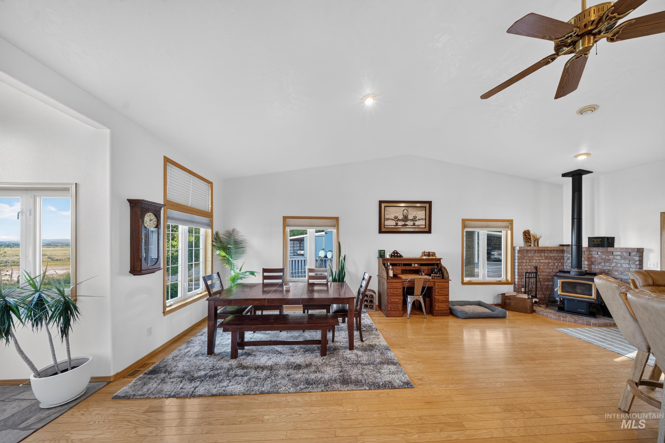 5540 Finley Road Fruitland, ID 83619 - Photo 33 of 50 Vaulted ceilings, wood-finish flooring, wood-burning stove with brick surround, multiple windows with wood trim, and a ceiling fan