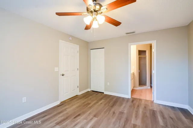 an empty room with wooden floor closet and ceiling fan