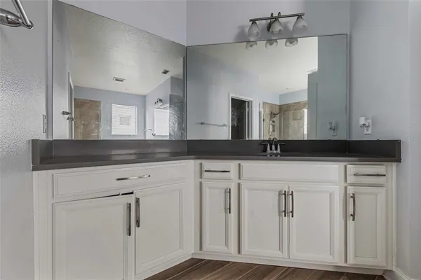 a spacious bathroom with a granite countertop sink a toilet a mirror and shower