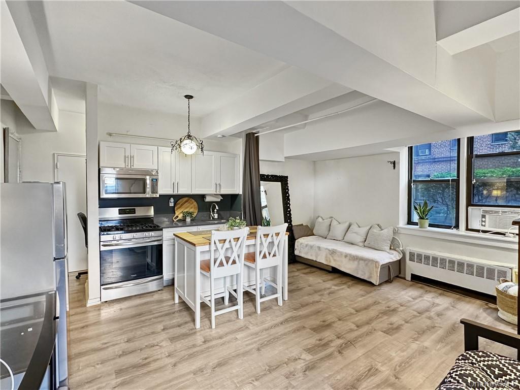 10 Franklin Avenue, Unit 1EFF White Plains, NY 10601 - Photo 2 of 13 a kitchen with stainless steel appliances granite countertop a stove top oven a sink dishwasher a dining table and chairs with wooden floor