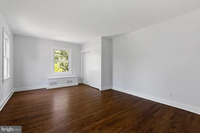 an empty room with wooden floor and window